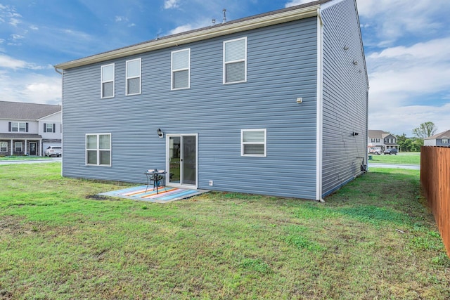 rear view of house with a lawn, fence, and a patio