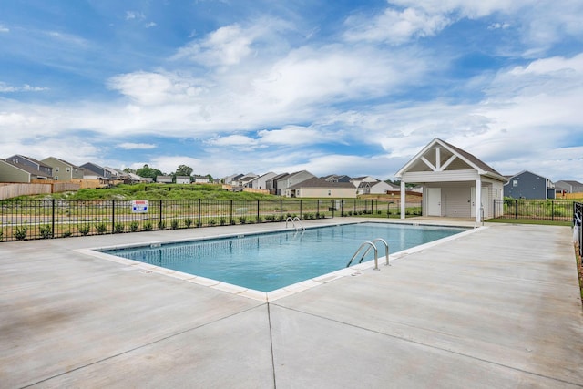 pool with a patio, fence, and a residential view