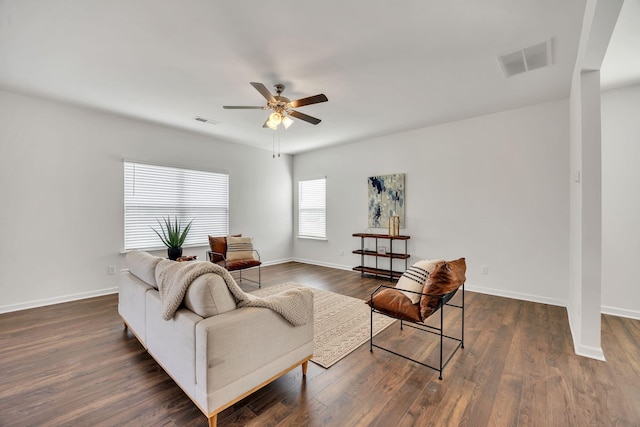 living room featuring visible vents, a ceiling fan, baseboards, and dark wood-style flooring