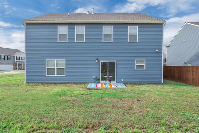 rear view of house with fence and a yard