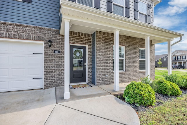 view of exterior entry featuring brick siding and a garage