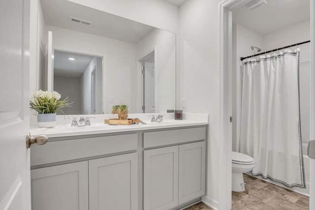 full bath featuring visible vents, a sink, double vanity, and toilet
