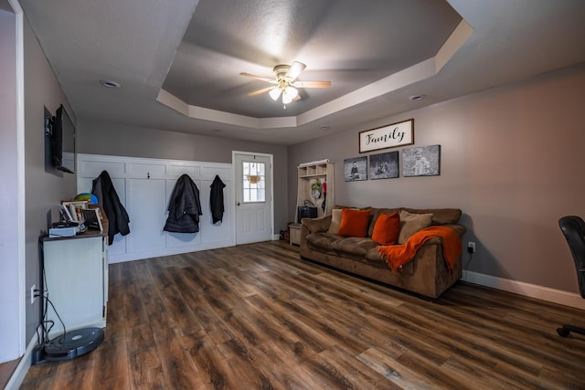 living room with baseboards, a ceiling fan, a raised ceiling, and wood finished floors