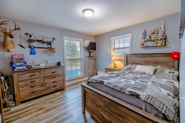 bedroom featuring a textured ceiling, multiple windows, and wood finished floors