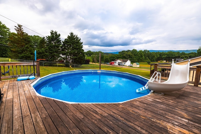 pool featuring a lawn, fence, and a deck