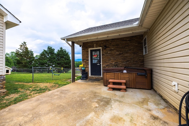 view of patio / terrace with a hot tub and fence