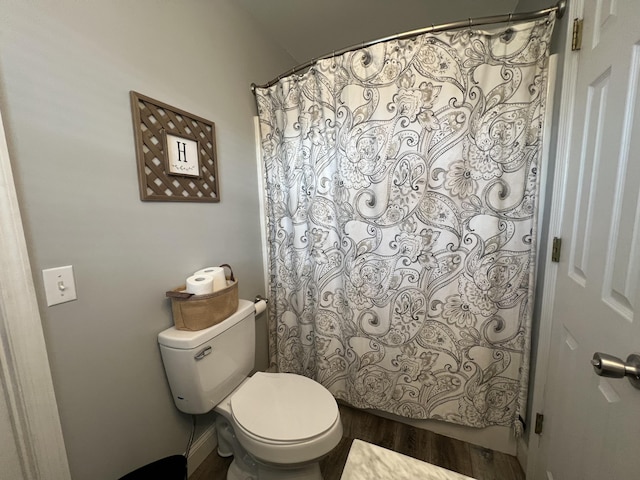 full bathroom with wood finished floors, toilet, and curtained shower
