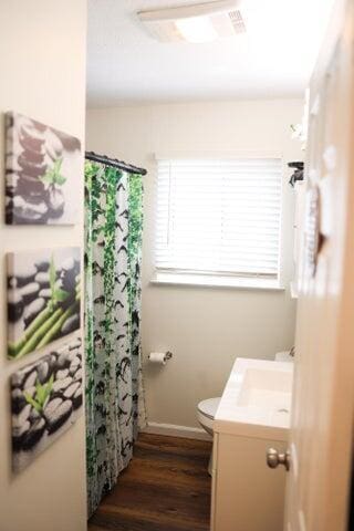 bathroom with vanity, toilet, baseboards, curtained shower, and wood finished floors