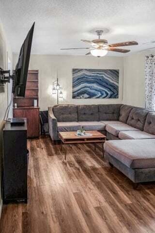 living area with a textured ceiling, ceiling fan, and wood finished floors