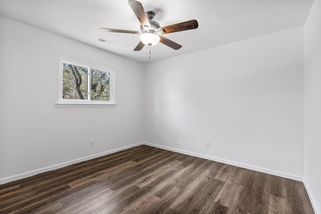 empty room featuring visible vents, a ceiling fan, baseboards, and dark wood-style floors