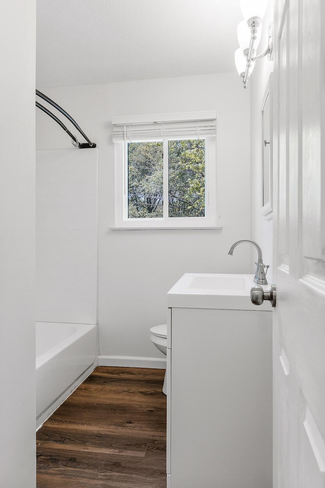 full bath featuring vanity, wood finished floors, bathing tub / shower combination, toilet, and baseboards
