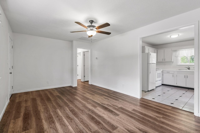 unfurnished living room featuring baseboards, a sink, ceiling fan, and wood finished floors
