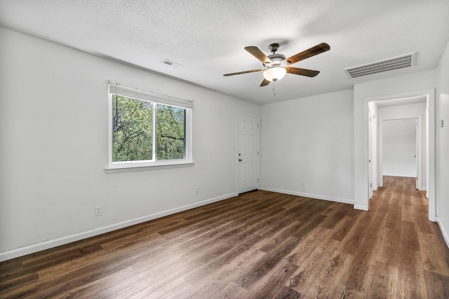 spare room with a ceiling fan, visible vents, and dark wood-type flooring