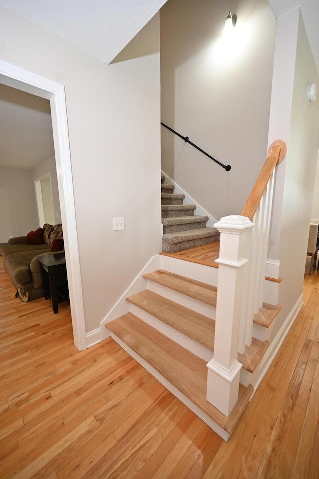 staircase featuring wood-type flooring and baseboards