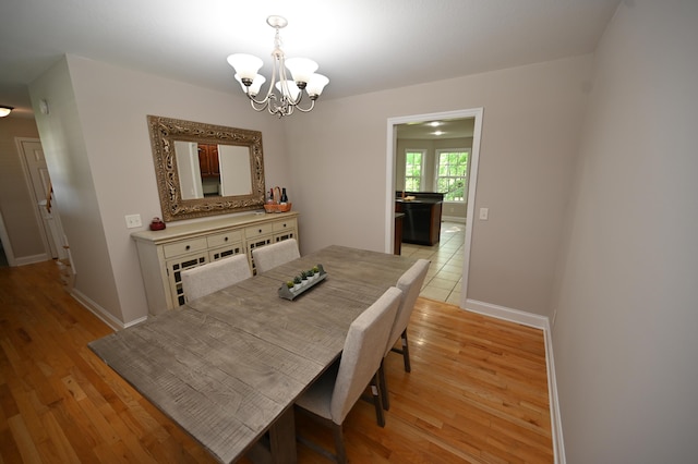 dining room with an inviting chandelier, baseboards, and light wood finished floors