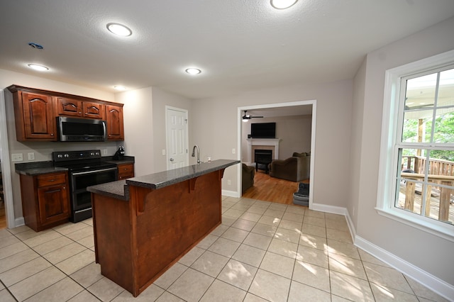 kitchen featuring light tile patterned flooring, dark countertops, a breakfast bar area, stainless steel microwave, and double oven range
