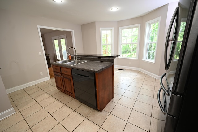 kitchen featuring a sink, light tile patterned floors, black appliances, and dark countertops