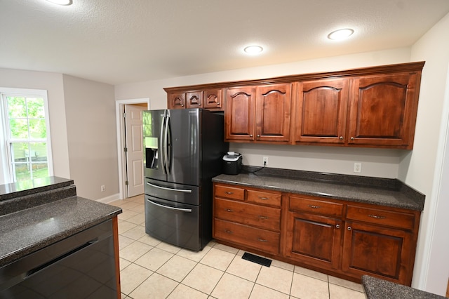 kitchen featuring a textured ceiling, dark countertops, light tile patterned floors, and black appliances
