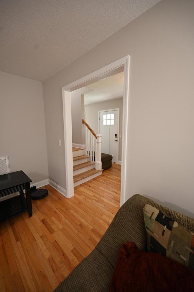 interior space featuring baseboards, light wood-style flooring, and stairway
