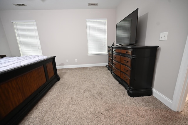 bedroom featuring visible vents, baseboards, and light carpet