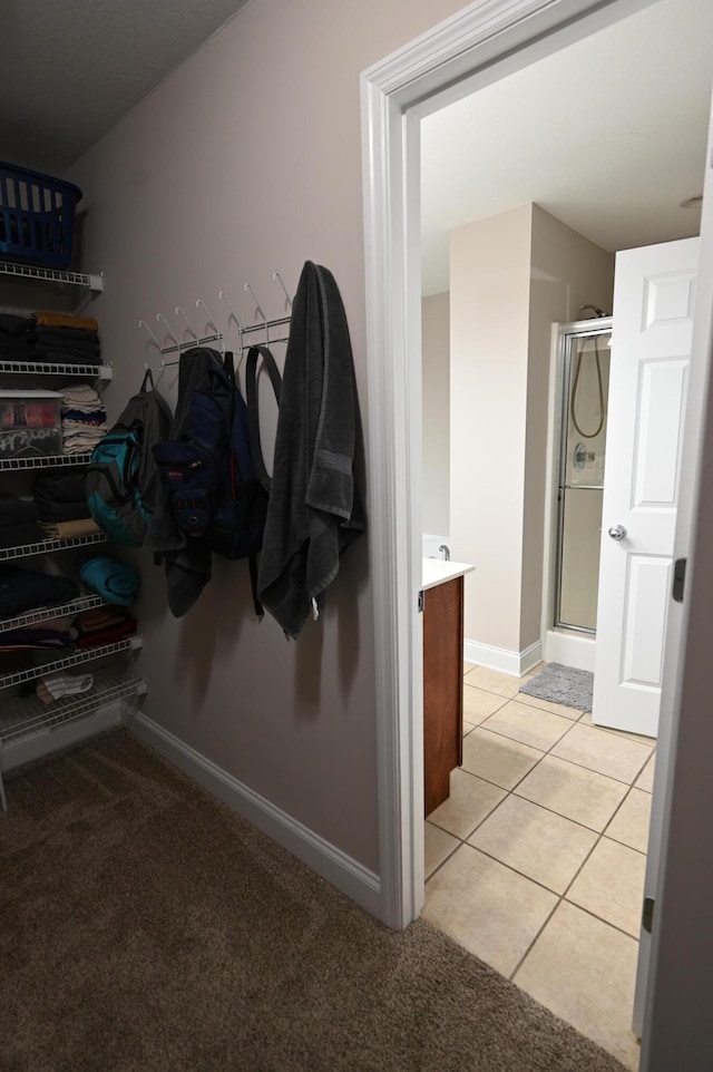 bathroom with vanity, tile patterned flooring, baseboards, and a stall shower