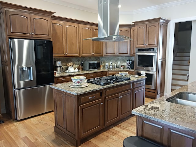 kitchen with crown molding, light stone counters, a center island, stainless steel appliances, and island range hood