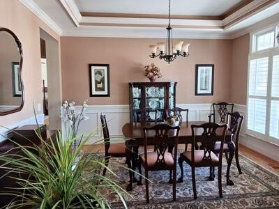 dining room featuring crown molding, a raised ceiling, wood finished floors, and a notable chandelier