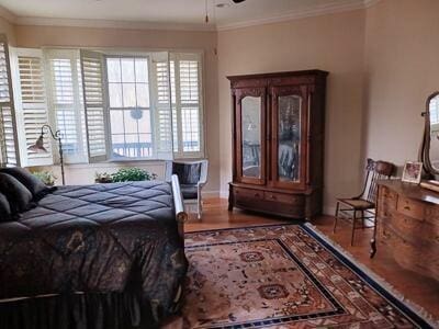 bedroom featuring ornamental molding and wood finished floors