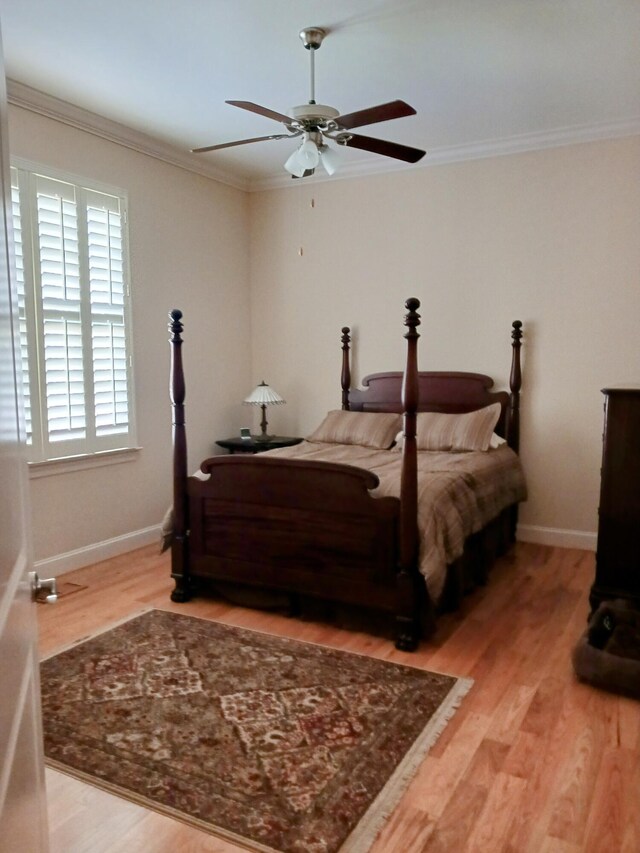 bedroom with crown molding, light wood-style flooring, ceiling fan, and baseboards
