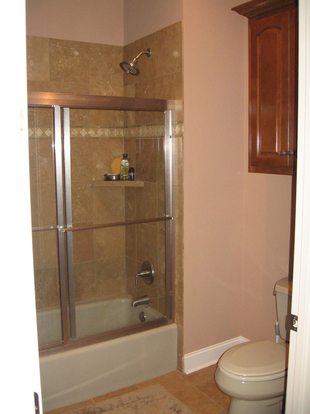 full bathroom featuring shower / bath combination with glass door, baseboards, tile patterned flooring, and toilet