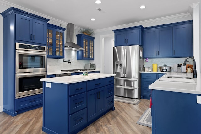 234 Reflection Dr, Dunlap, TN 37327 - kitchen featuring appliances with stainless steel finishes, wall chimney range hood, a sink, blue cabinetry, and ornamental molding