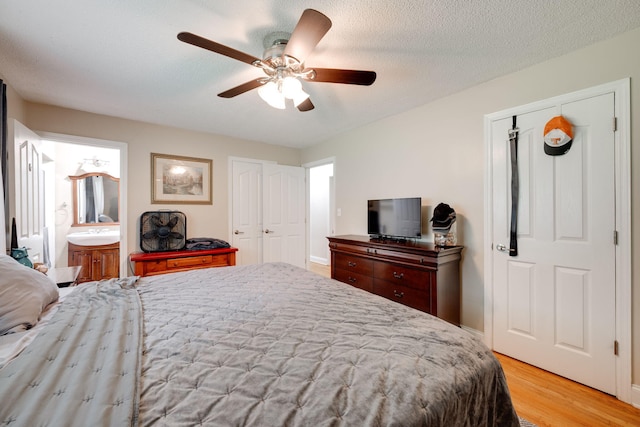 bedroom featuring baseboards, ensuite bathroom, a ceiling fan, and light wood finished floors