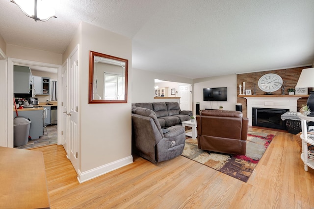 living room with baseboards, light wood-style flooring, and a fireplace