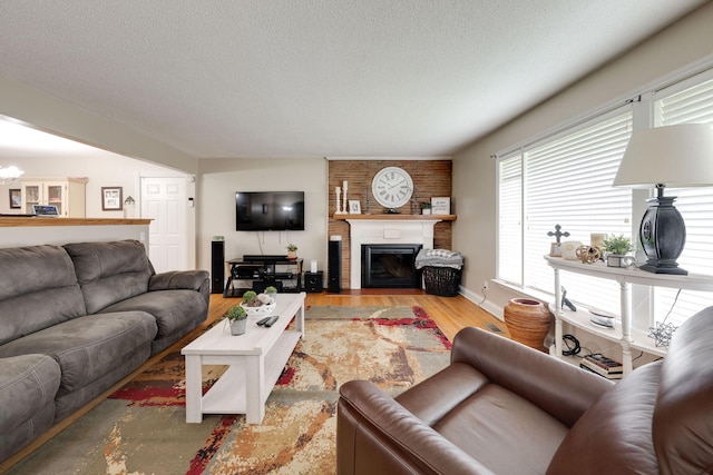 living room featuring a fireplace with flush hearth, a textured ceiling, a chandelier, and light wood-style flooring