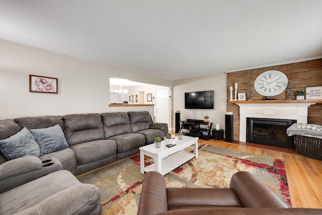 living area featuring an inviting chandelier, a textured ceiling, a fireplace, and wood finished floors