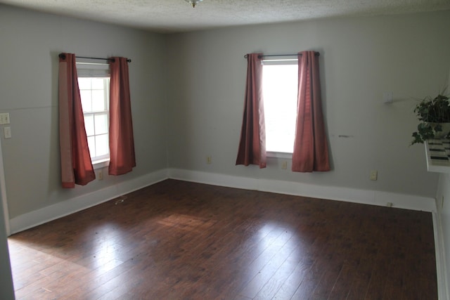 empty room featuring a textured ceiling, baseboards, and hardwood / wood-style floors