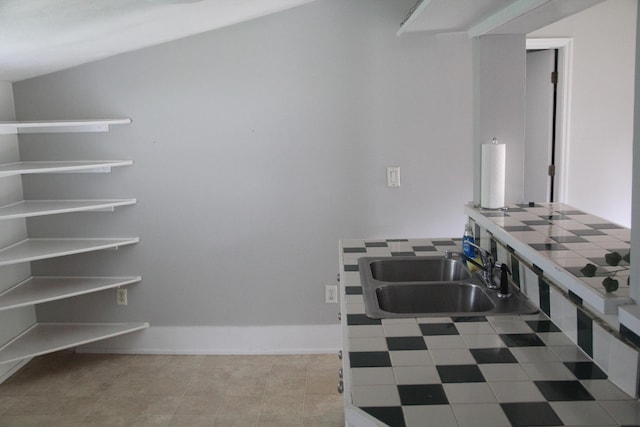 interior space featuring baseboards, tile patterned floors, and a sink
