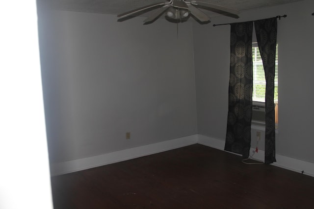 empty room featuring baseboards, a ceiling fan, and dark wood-style floors