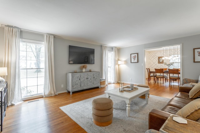living room with crown molding, visible vents, and wood finished floors
