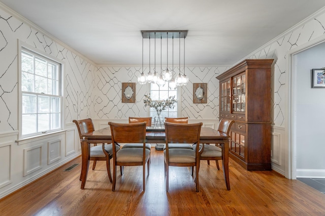 dining area with wallpapered walls, visible vents, a decorative wall, an accent wall, and wood finished floors