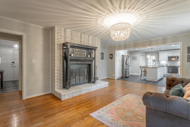 living room with crown molding, dark wood-type flooring, baseboards, and a brick fireplace