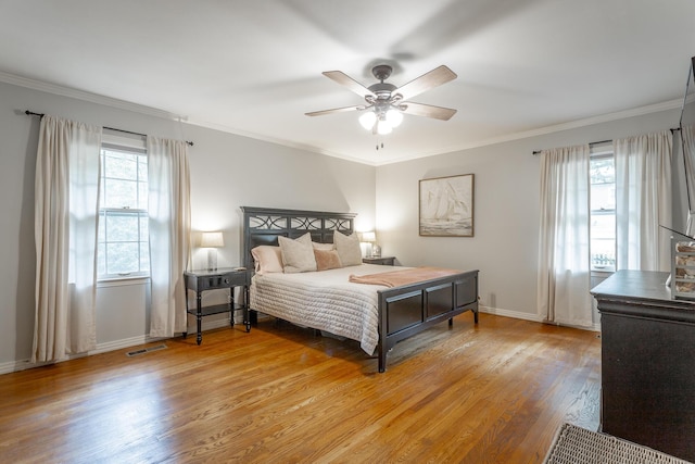 bedroom with baseboards, light wood finished floors, crown molding, and a ceiling fan