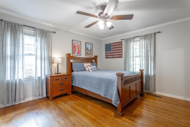 bedroom featuring multiple windows, light wood-style flooring, and ornamental molding