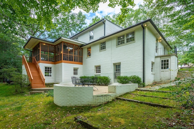 rear view of property featuring a sunroom, a patio, brick siding, and stairs