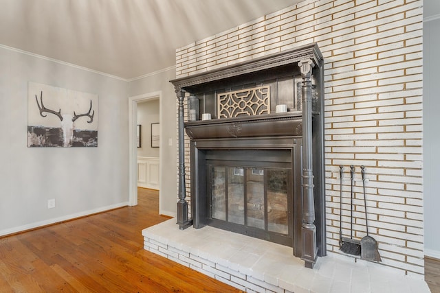 interior details with a brick fireplace, wood finished floors, baseboards, and ornamental molding