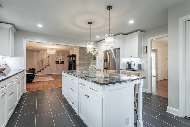 kitchen featuring dark tile patterned flooring, stainless steel fridge, a center island, and a notable chandelier