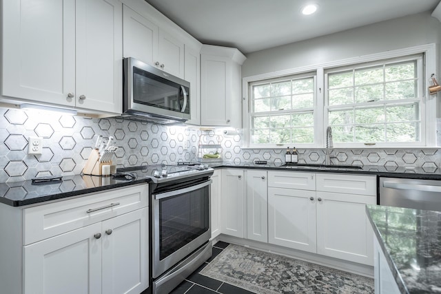 kitchen featuring white cabinets, decorative backsplash, stainless steel appliances, and a sink