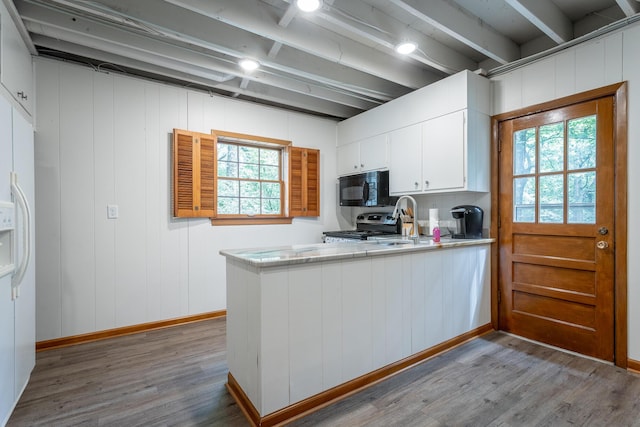 kitchen featuring stainless steel electric range oven, black microwave, white cabinets, and wood finished floors