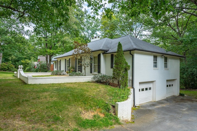 view of front of property with a front yard, an attached garage, a chimney, and driveway