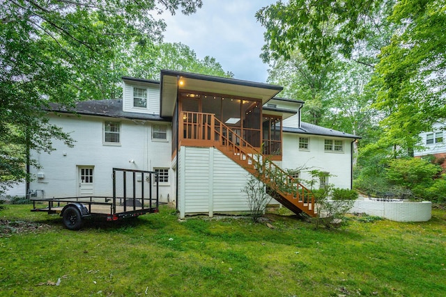 rear view of property featuring a yard, a sunroom, stairs, and brick siding